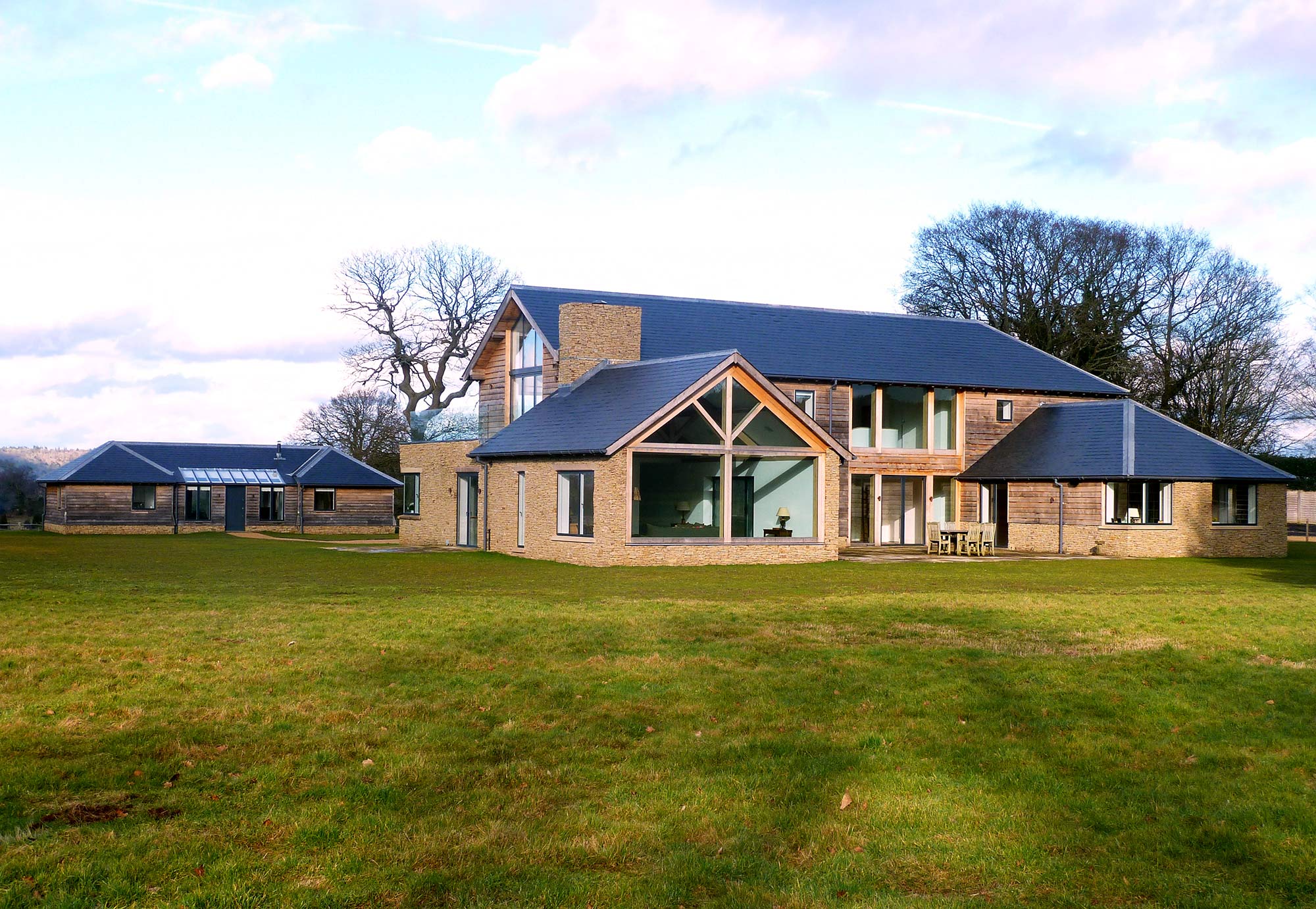 Rear view of New build home with oak frame, stone and specialist glass - Castle Eaton Construction, Surrey