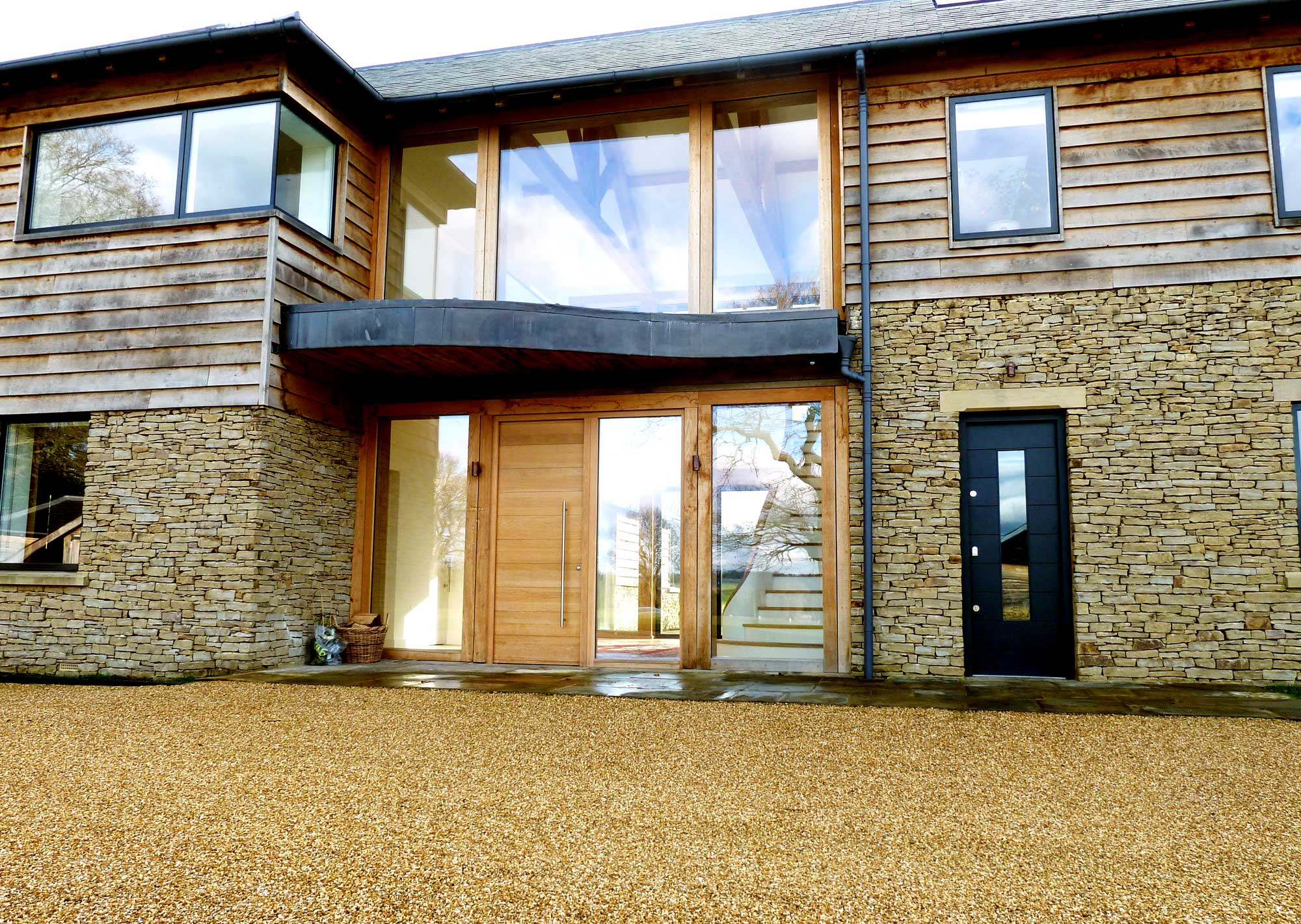 Front entrance to New build home with oak frame, stone and specialist glass - Castle Eaton Construction, Surrey